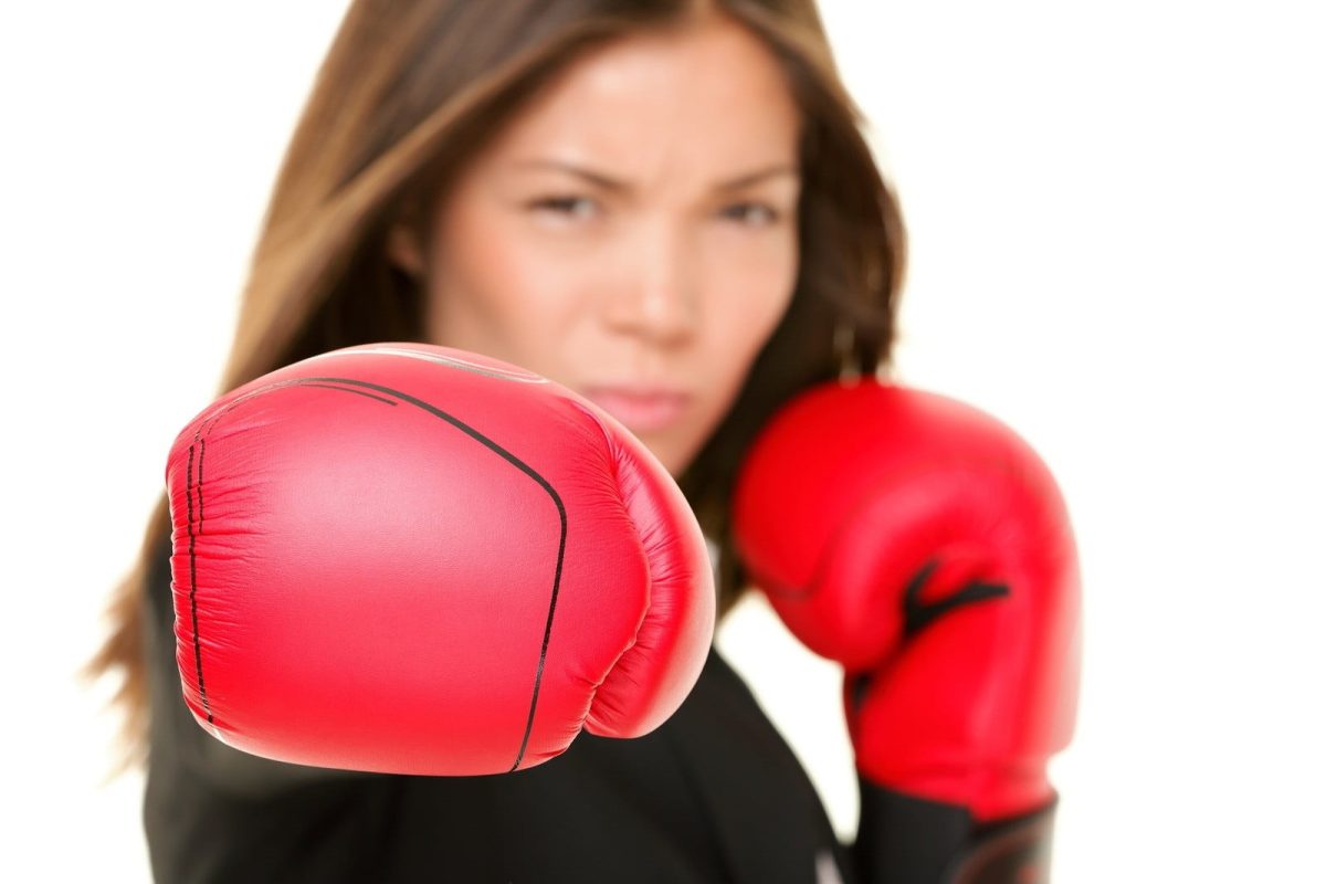 Boxing business woman punching towards camera wearing boxing glo